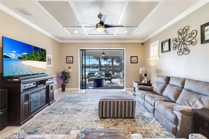 Living room with ceiling fan, light tile patterned flooring, and ornamental molding