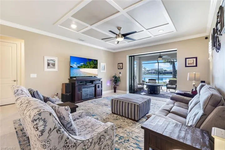 Living room featuring ceiling fan, ornamental molding, and coffered ceiling