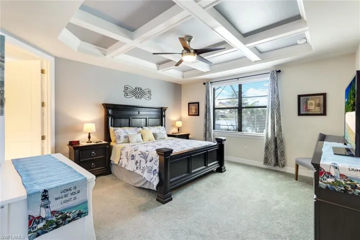 Carpeted bedroom with ceiling fan, beam ceiling, and coffered ceiling