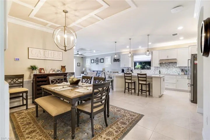Tiled dining room with ceiling fan with notable chandelier and ornamental molding