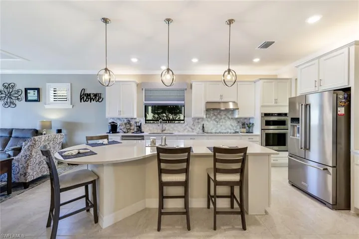 Kitchen with a kitchen bar, white cabinets, a kitchen island, and appliances with stainless steel finishes