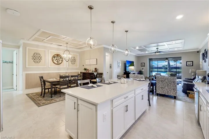 Kitchen with a center island, decorative light fixtures, white cabinetry, and ceiling fan