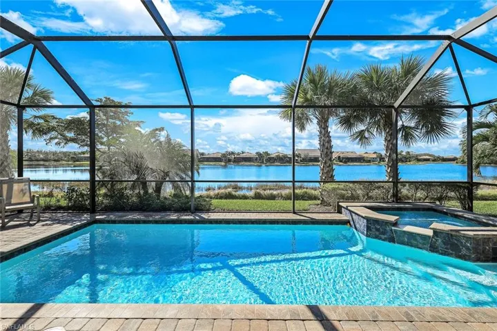 View of swimming pool with glass enclosure, a water view, and an in ground hot tub