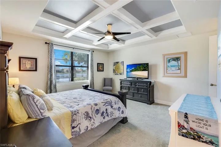 Carpeted bedroom featuring beam ceiling, ceiling fan, and coffered ceiling