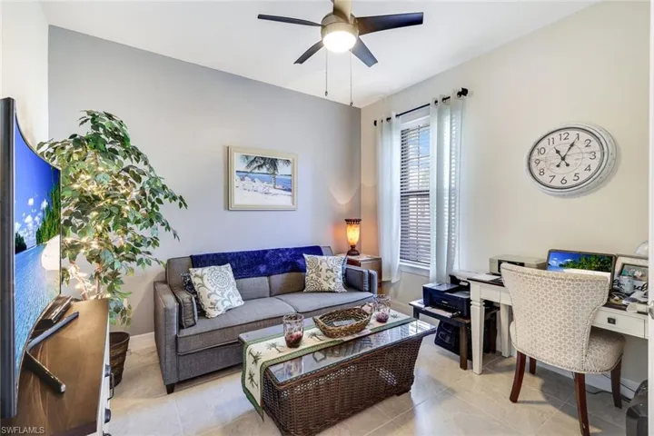 Living room with ceiling fan and light tile patterned flooring