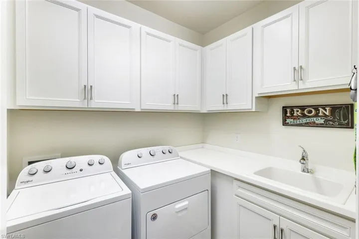 Laundry area with washer and clothes dryer, cabinets, and sink