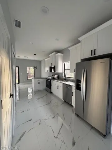 Kitchen with white cabinets, refrigerator, stove, and dishwashing machine