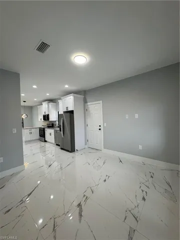 Kitchen featuring sink, white cabinets, refrigerator, stove, and pendant lighting