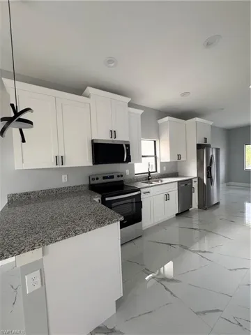 Kitchen featuring sink, fridge, white cabinets, dishwasher, and stove