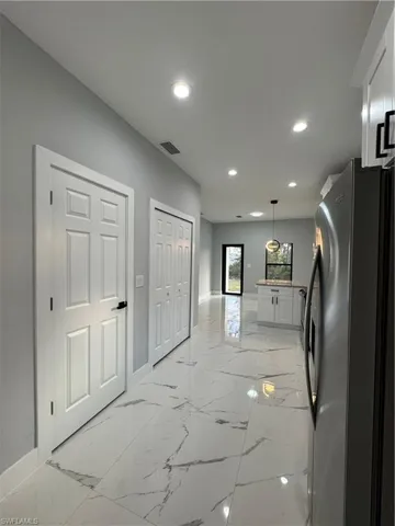 Kitchen with pendant lighting, white cabinetry, and fridge