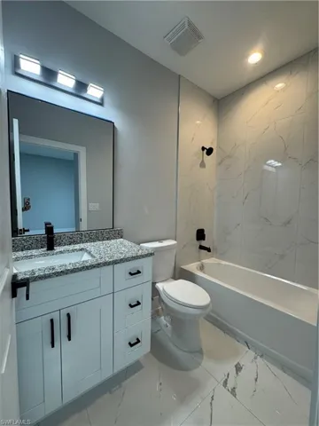 Full bathroom featuring toilet, vanity, and tiled shower / bath