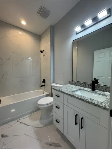 Full guess bathroom with toilet, tiled shower / bath, and vanity
