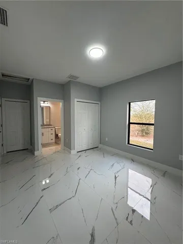 Unfurnished bedroom with ensuite bathroom and a closet