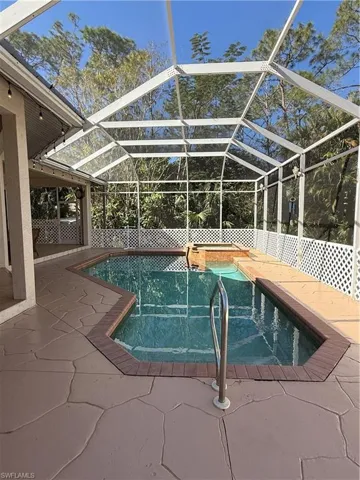 View of pool with a patio, glass enclosure, and ceiling fan