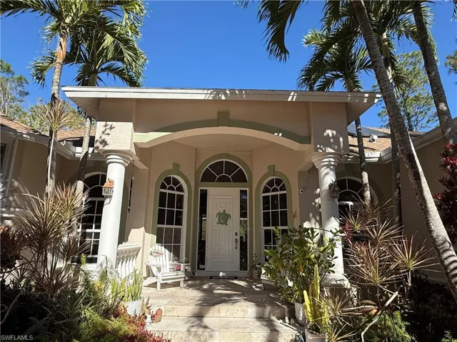 Tiled foyer with decorative columns, crown molding, a healthy amount of sunlight, and a notable chandelier
