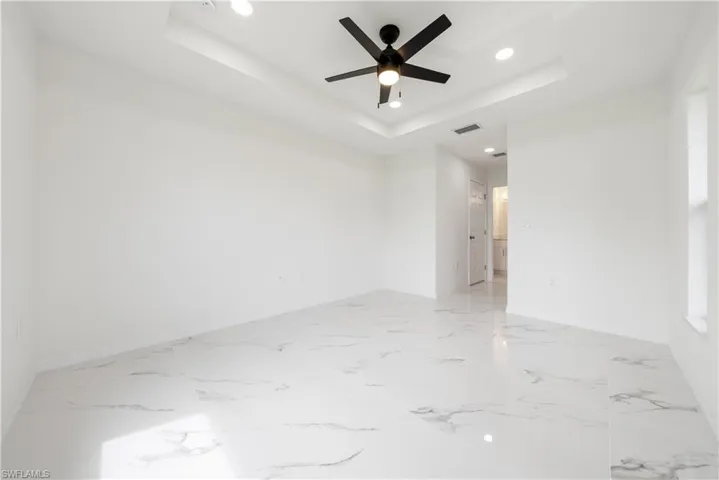 Unfurnished room featuring ceiling fan and a raised ceiling