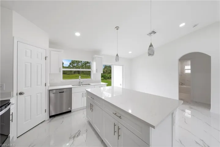 Kitchen featuring appliances with stainless steel finishes, white cabinetry, a center island, and pendant lighting