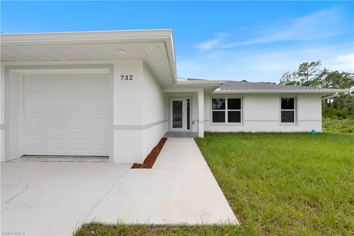 Entrance to property with a garage and a lawn
