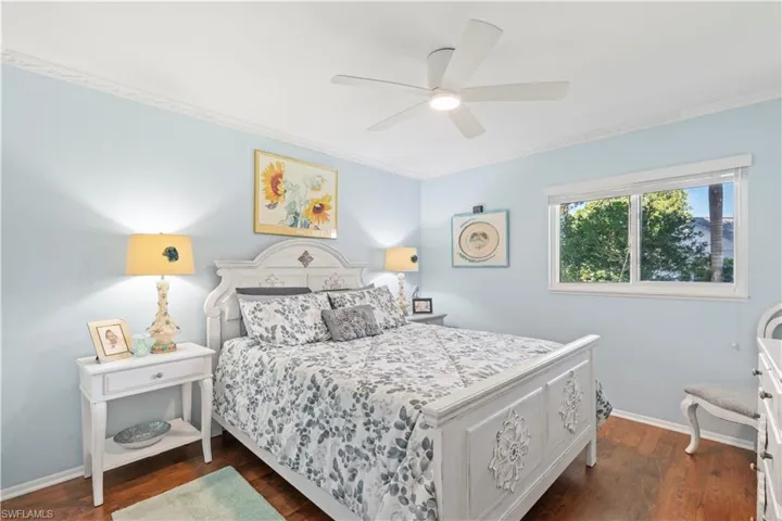 Bedroom featuring dark wood finished floors, ornamental molding, and a ceiling fan