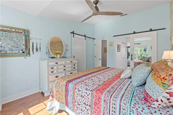 Bedroom with a barn door, wood finished floors, and ceiling fan
