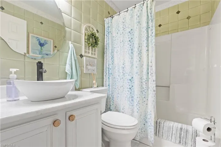 Bathroom featuring tile walls, vanity, and shower / bath combination with curtain