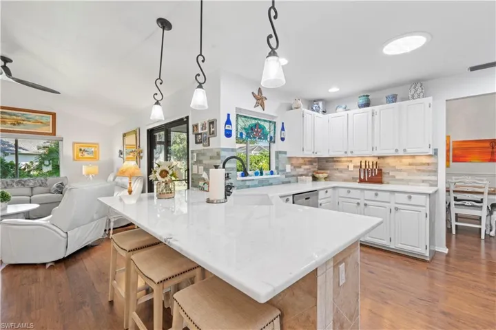 Kitchen with a peninsula, plenty of natural light, tasteful backsplash, wood finished floors, and lofted ceiling