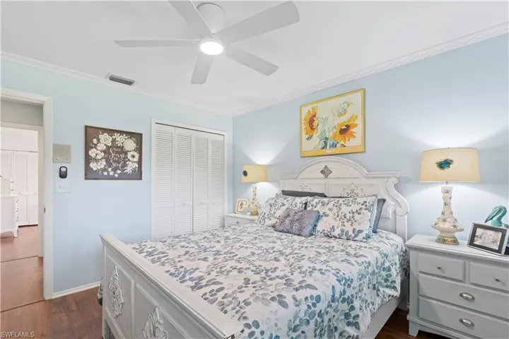 Bedroom with a closet, ornamental molding, dark wood-style flooring, and ceiling fan
