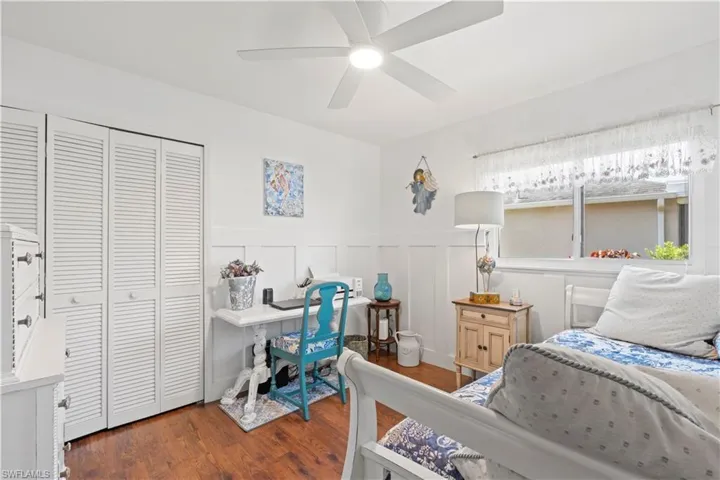 Bedroom featuring wood finished floors, a wainscoted wall, a closet, and a ceiling fan
