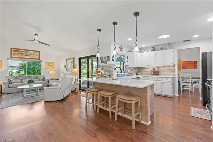 Kitchen with a peninsula, decorative backsplash, dark wood-style floors, a kitchen breakfast bar, and recessed lighting