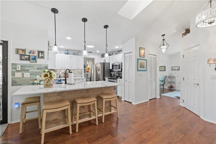 Kitchen with appliances with stainless steel finishes, a peninsula, white cabinets, decorative backsplash, and a breakfast bar area
