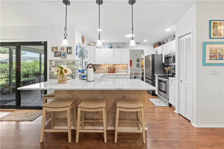 Kitchen featuring stainless steel appliances, decorative backsplash, a breakfast bar, white cabinets, and recessed lighting