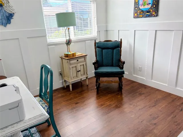 Living area with a decorative wall, wood finished floors, and a wainscoted wall