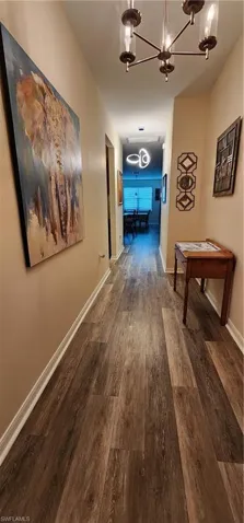 Hallway with dark wood-style floors and a chandelier