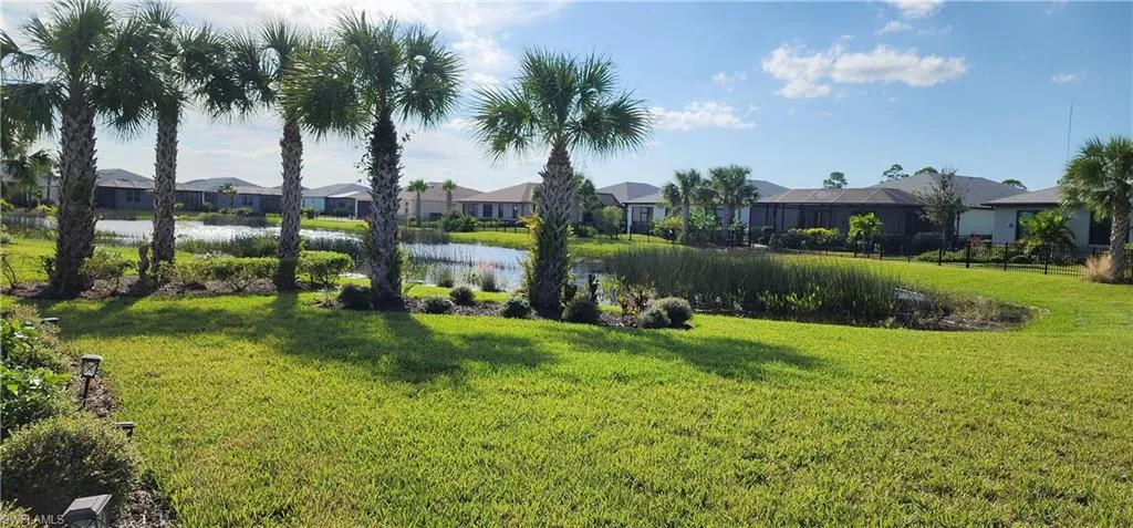 View of green lawn featuring a residential view and a water view