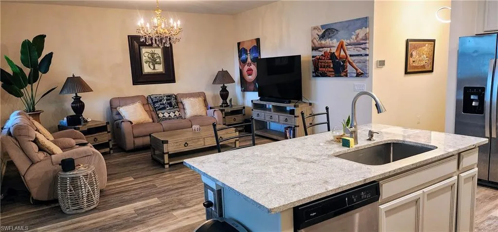 Kitchen featuring a center island with sink, stainless steel appliances, light wood finished floors, and open floor plan