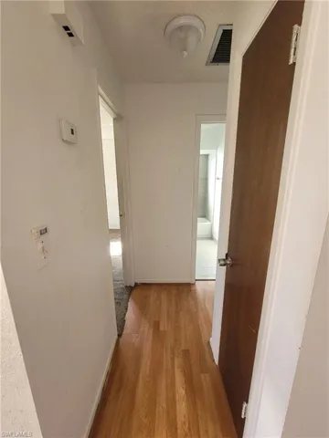 Hallway with light wood-style flooring and a textured ceiling
