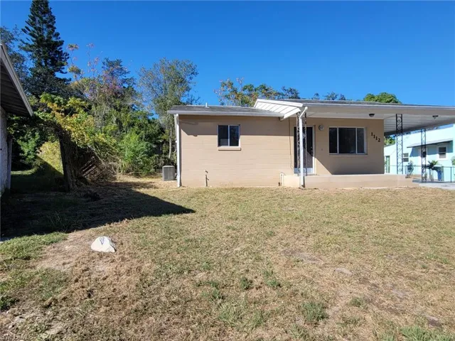 Back of property with a lawn, a patio area, and a carport