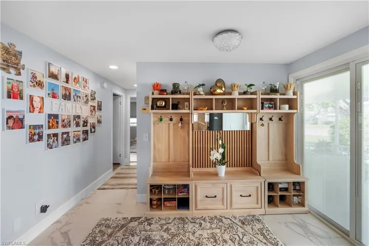 Entryway featuring wood-finish built-in storage, a sliding glass door, recessed lighting, and large format tile flooring