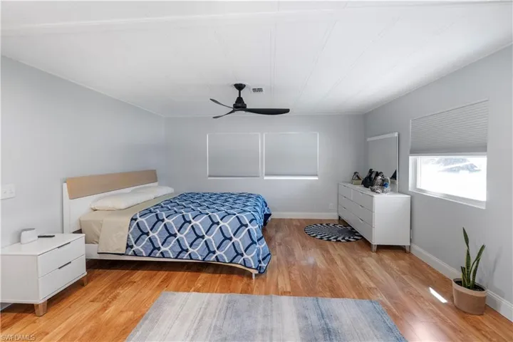 Spacious room featuring wood-finish flooring, light gray wall paint, and a white paneled ceiling