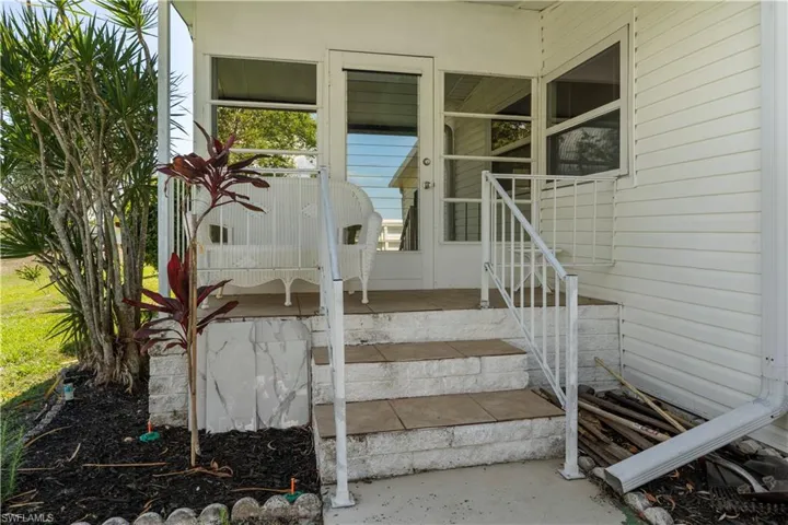 Entryway featuring a three-step staircase with a white metal railing, tile treads, and a white siding exterior