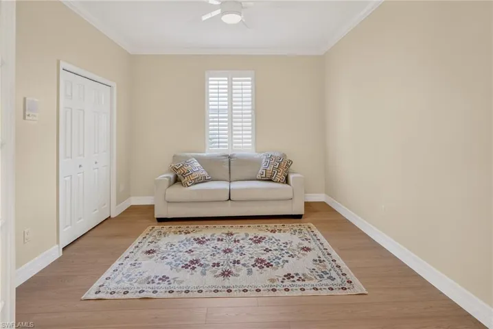 Sitting room with light wood-type flooring, crown molding, and ceiling fan