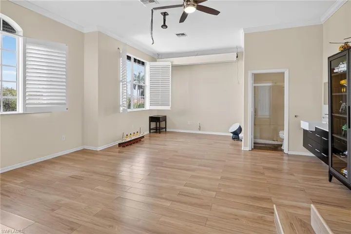 Unfurnished living room with ornamental molding, light wood-type flooring, and ceiling fan