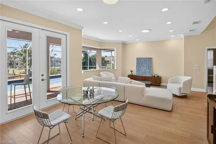 Dining area with recessed lighting, light wood finished floors, french doors, and ornamental molding