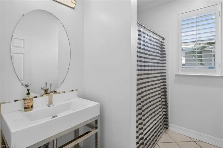 Full bath featuring curtained shower and light tile patterned floors