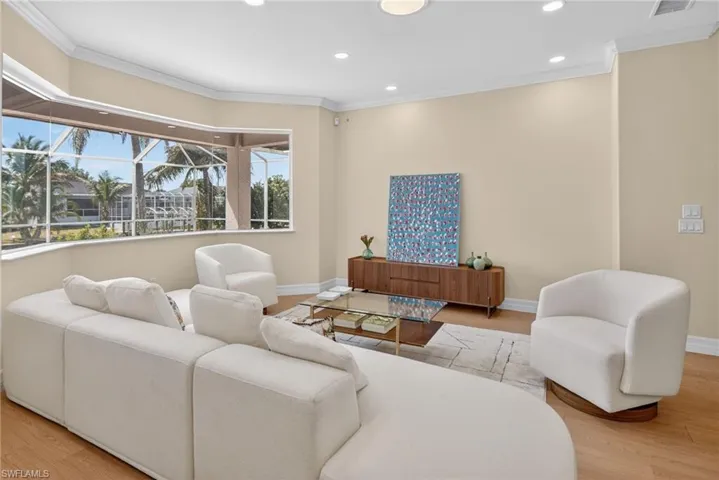 Living room featuring light wood-type flooring, ornamental molding, and recessed lighting