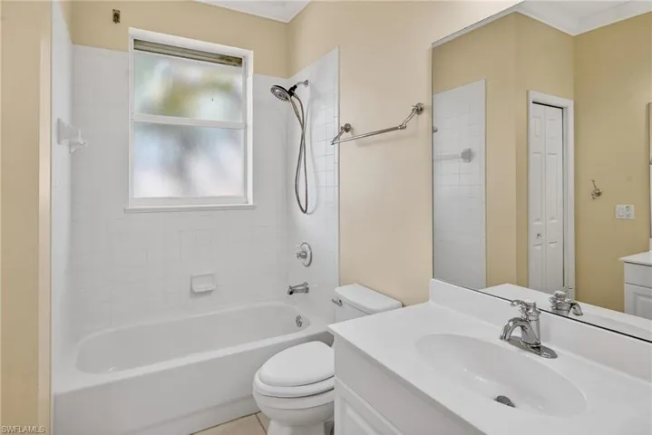 Bathroom with vanity, washtub / shower combination, crown molding, and a closet