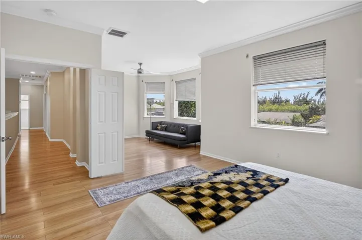 Bedroom with crown molding, light wood-style floors, and a ceiling fan