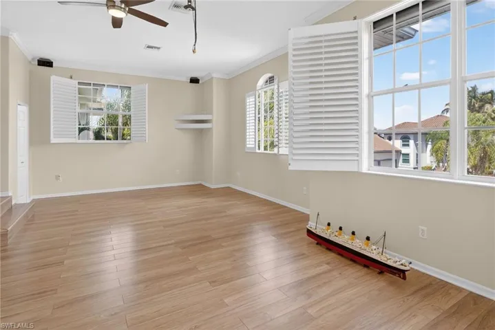 Empty room featuring crown molding, light wood-style flooring, and a ceiling fan