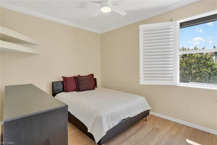Bedroom featuring ornamental molding, light wood finished floors, and ceiling fan