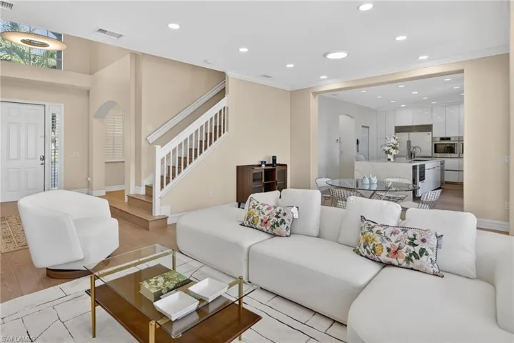 Living room featuring arched walkways, recessed lighting, light wood-style flooring, and ornamental molding